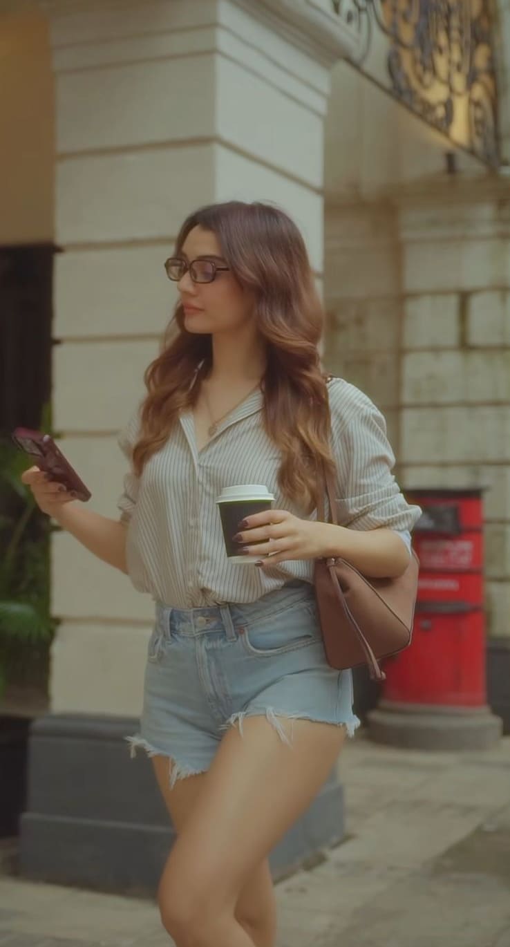 Striped beige button-down shirt with high-waist denim shorts and brown sling bag