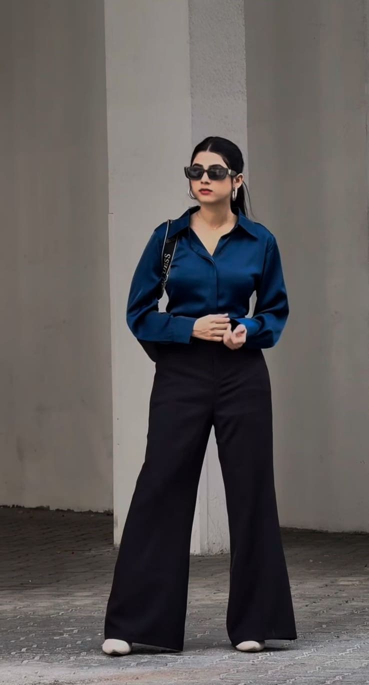 Teal blue satin shirt with wide-leg black trousers and rectangular sunglasses